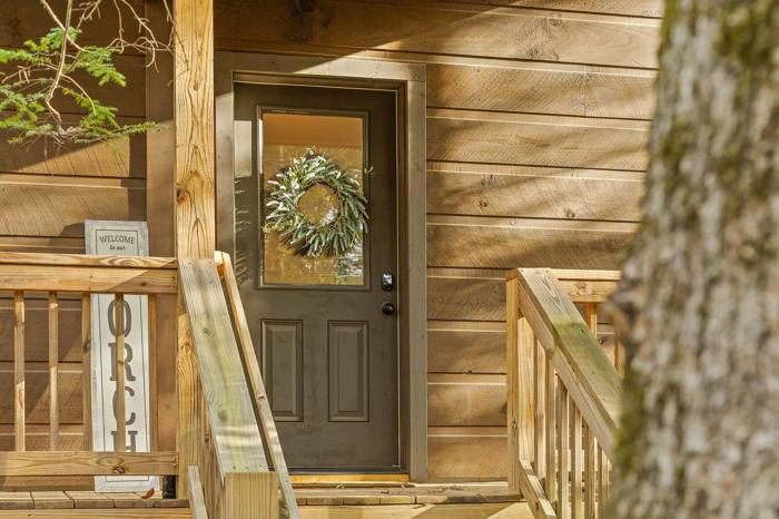 A wooden cabin with a door, a welcome sign, and a wreath.