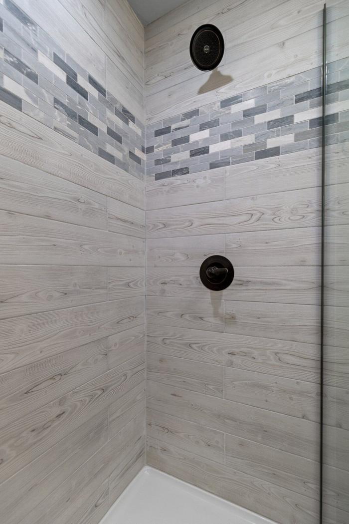 A shower area with a wooden panel wall and a tiled shower floor.