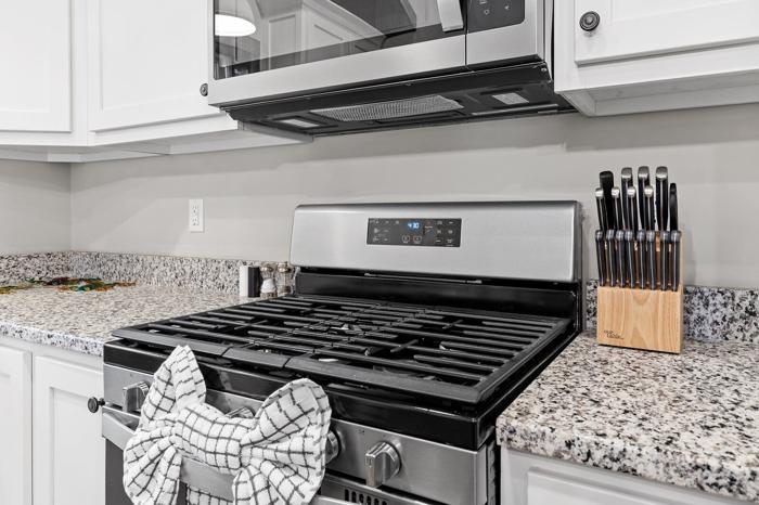 A kitchen with a stainless steel stove, a microwave above it, and a knife block on the counter.