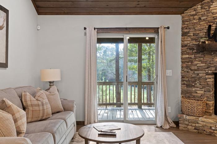 A living room with a sofa, a coffee table, a fireplace, and a sliding glass door to a deck.