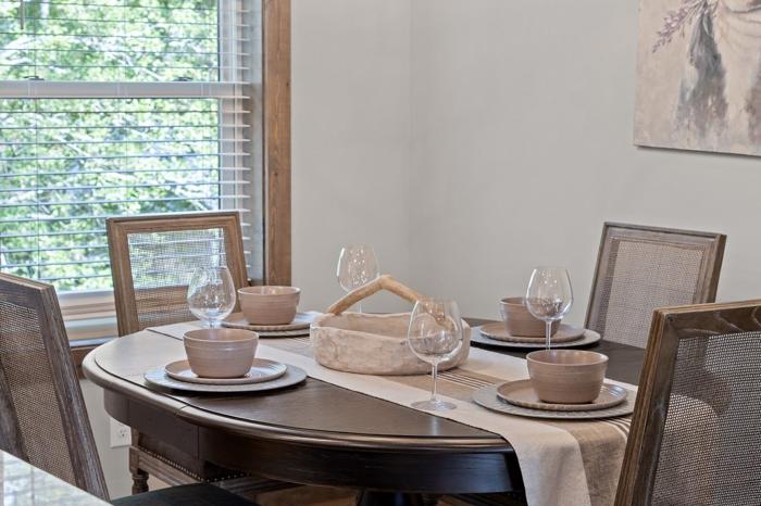 A dining table set with bowls and wine glasses, surrounded by chairs.