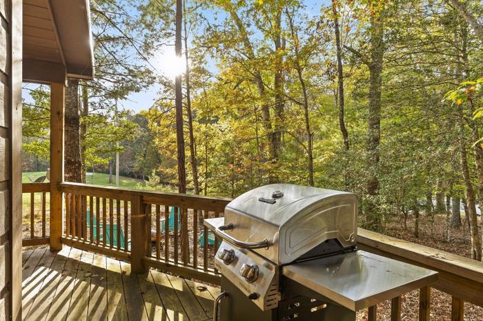 A wooden deck with a grill and a view of a forest.