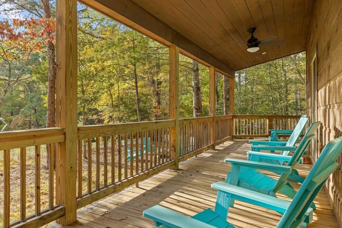 A wooden deck with chairs and a ceiling fan.
