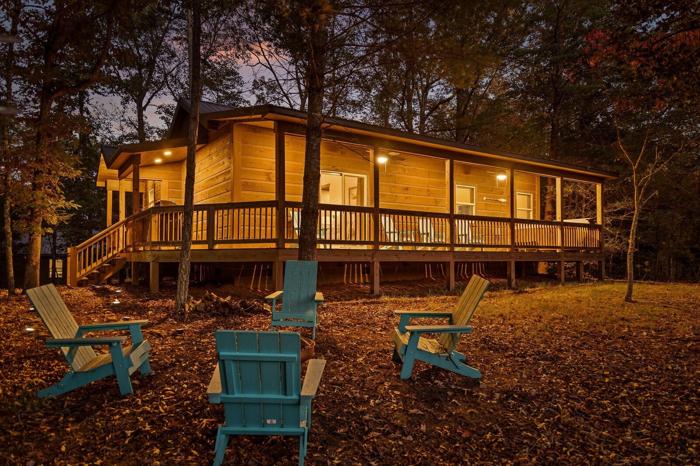 A wooden cabin with a deck, surrounded by trees.