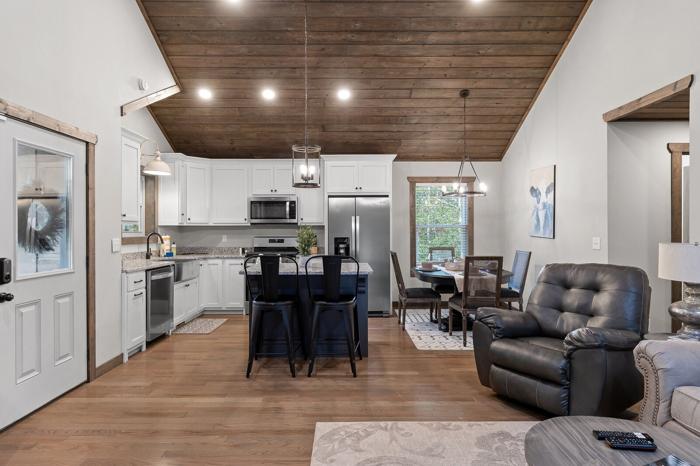 A modern kitchen with white cabinets, a central island, and a dining area with a leather chair and table.