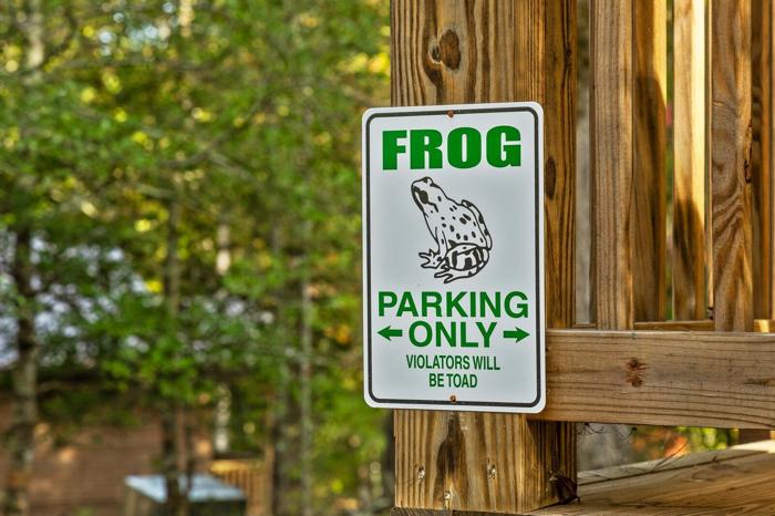 A sign with a frog illustration and text indicating parking directions and a warning about toads.