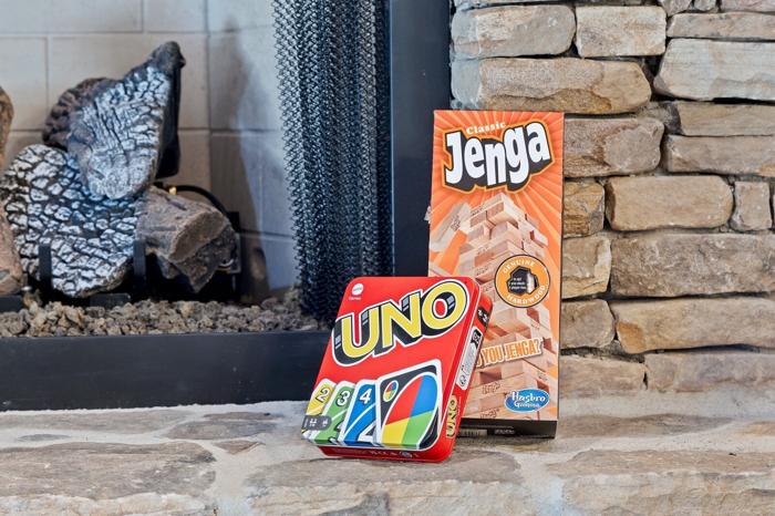 A board game, UNO, and a Jenga box on a stone surface.